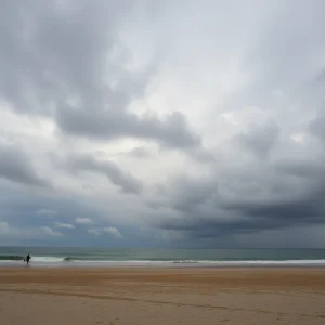 A beach scene in Huntington Beach under dark clouds symbolizing sorrow.